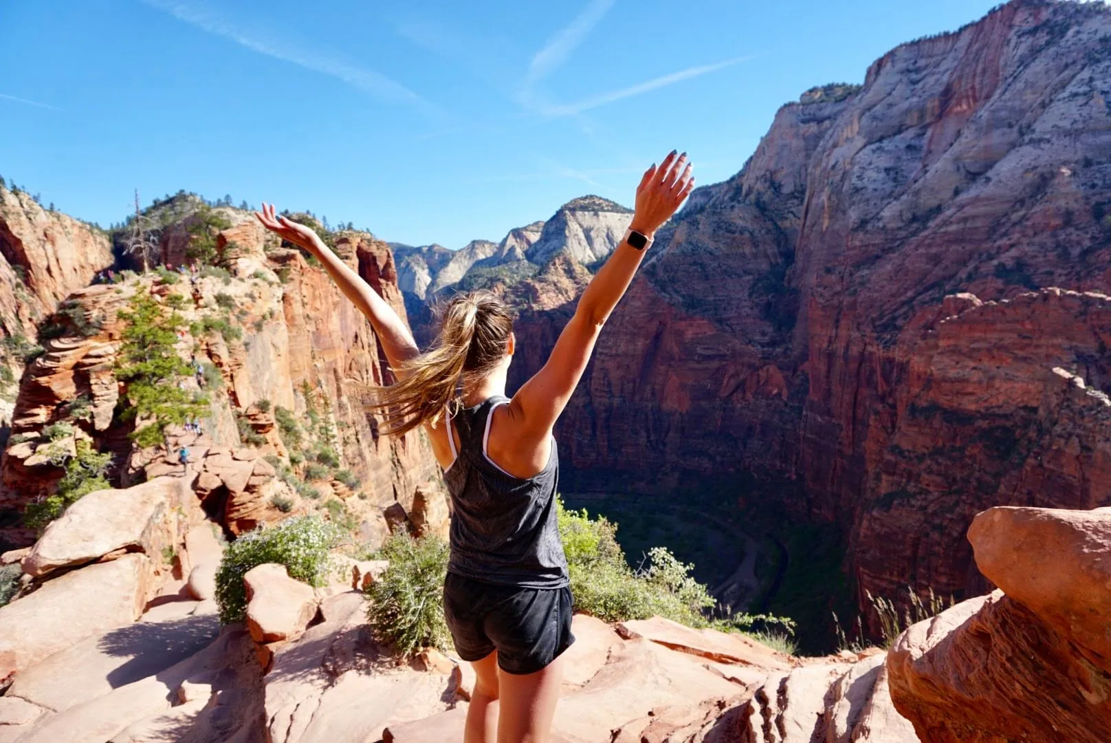 Kiersten with her arms up on a red rock ledge in Zion National Park
