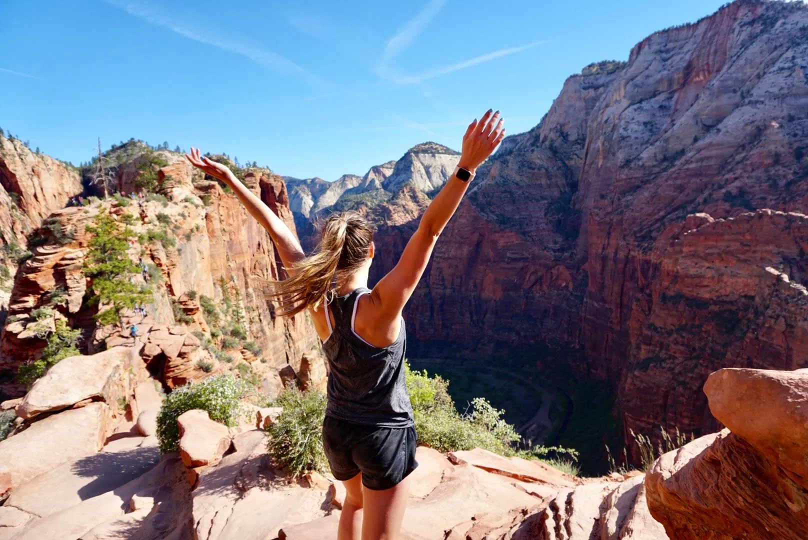 Kiersten with her arms up on a red rock ledge in Zion National Park
