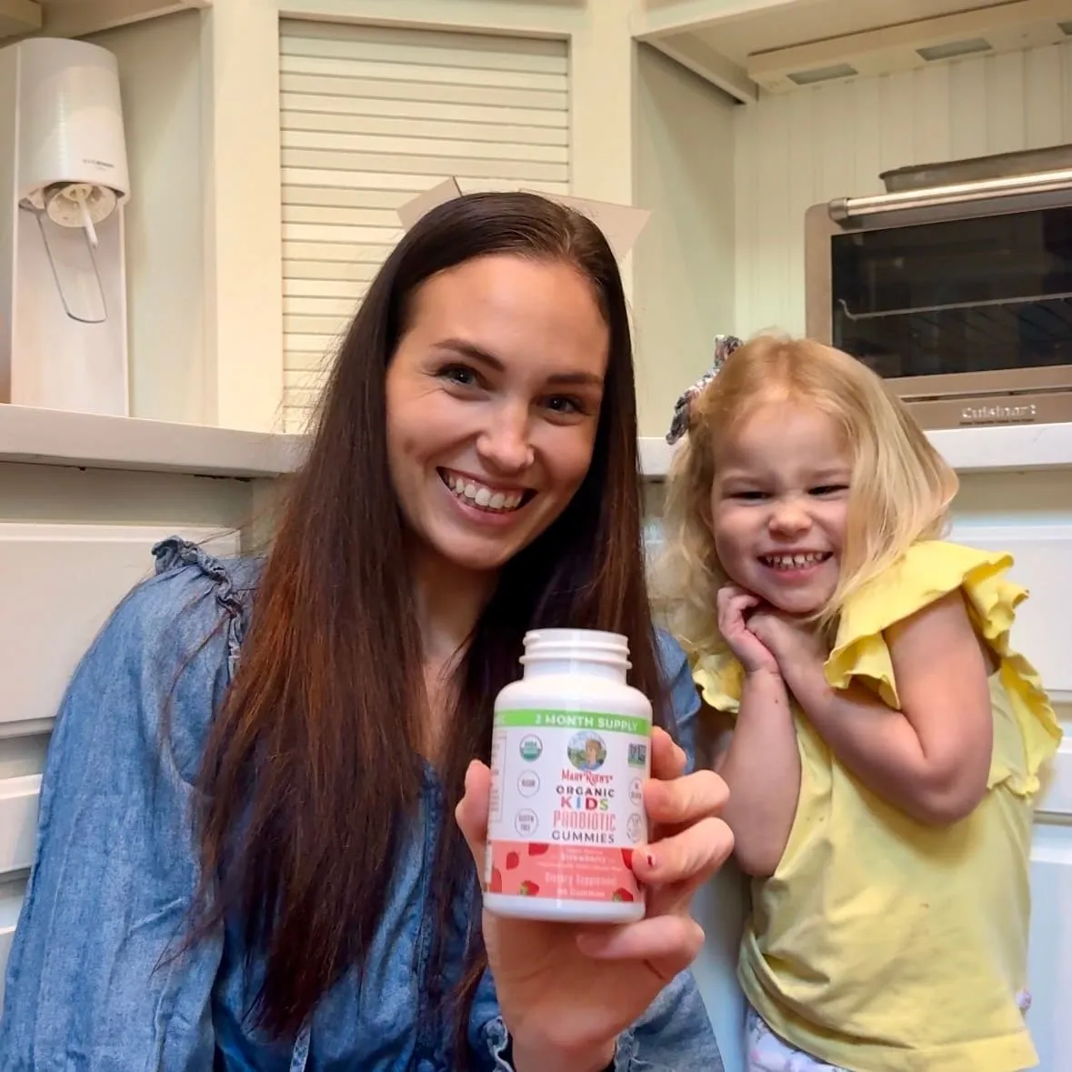 Kiersten and her toddler in the kitchen holding a bottle of children’s vitamins