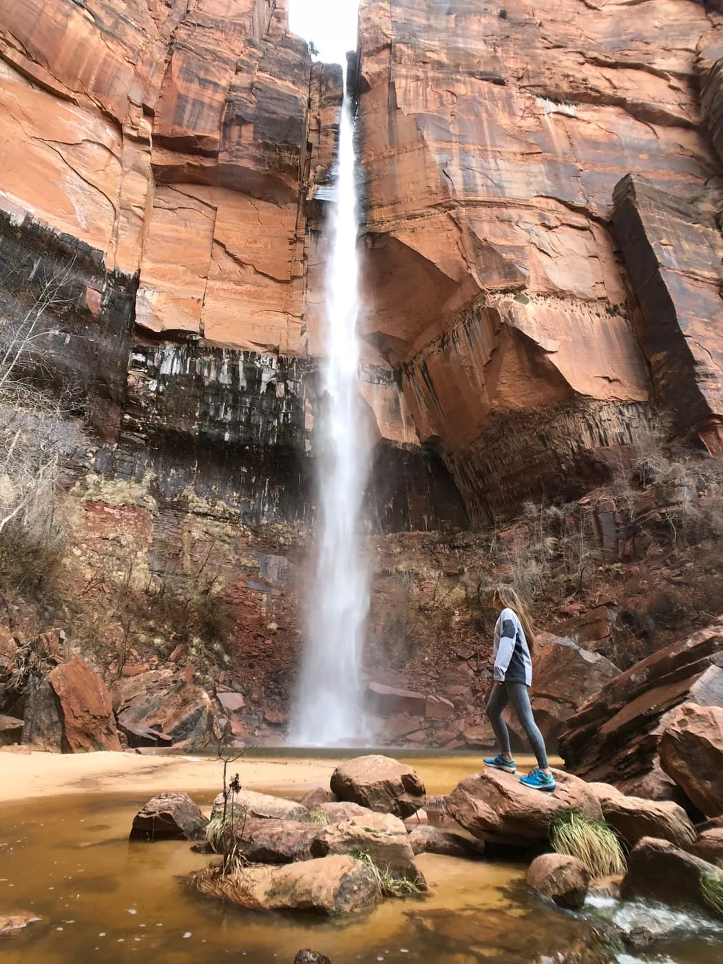 A waterfall pouring over the red rock at the Emerald Pools in Zion