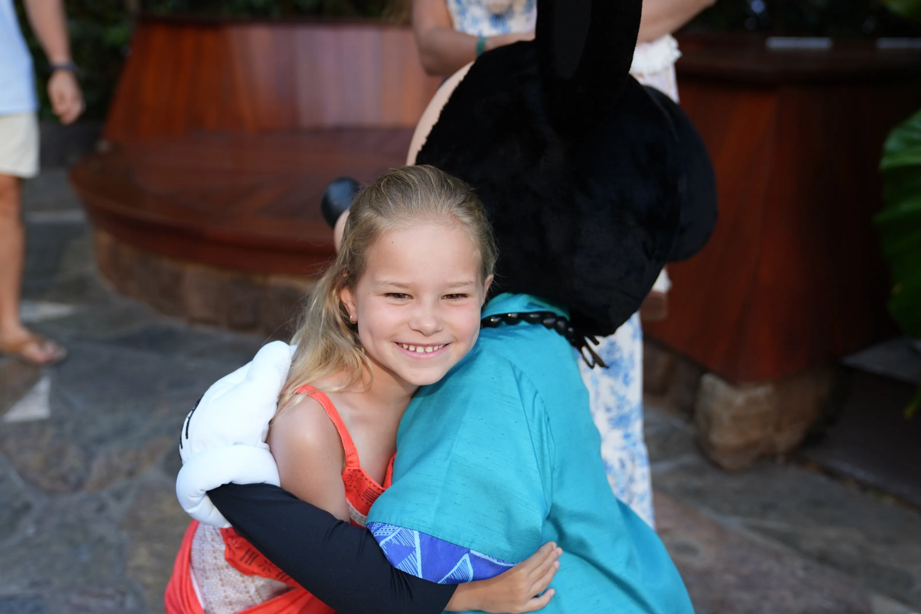 Addie hugging Mickey Mouse and grinning over his shoulder